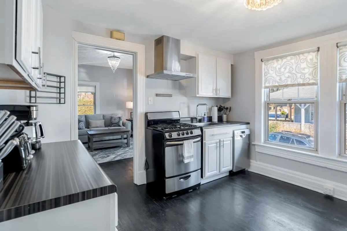 This image showcases a modern kitchen bathed in natural light, with contemporary appliances and a decorative light fixture. The scene suggests activity and warmth, hinting at home-cooked meals and shared family moments.